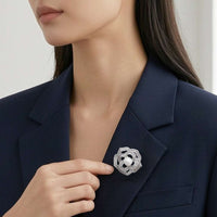 A close-up of a woman wearing a navy blazer with a flower-shaped cubic zirconia brooch pinned to her blazer lapel.