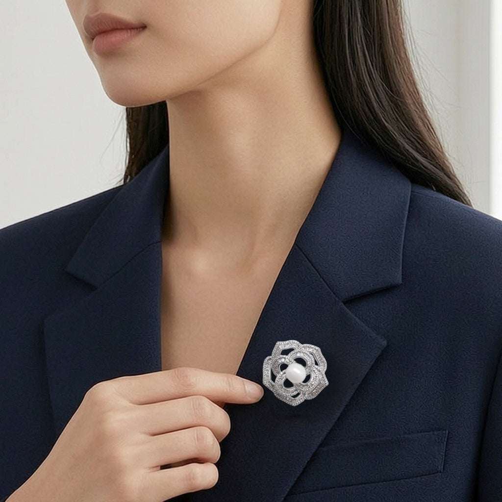 A close-up of a woman wearing a navy blazer with a flower-shaped cubic zirconia brooch pinned to her blazer lapel.