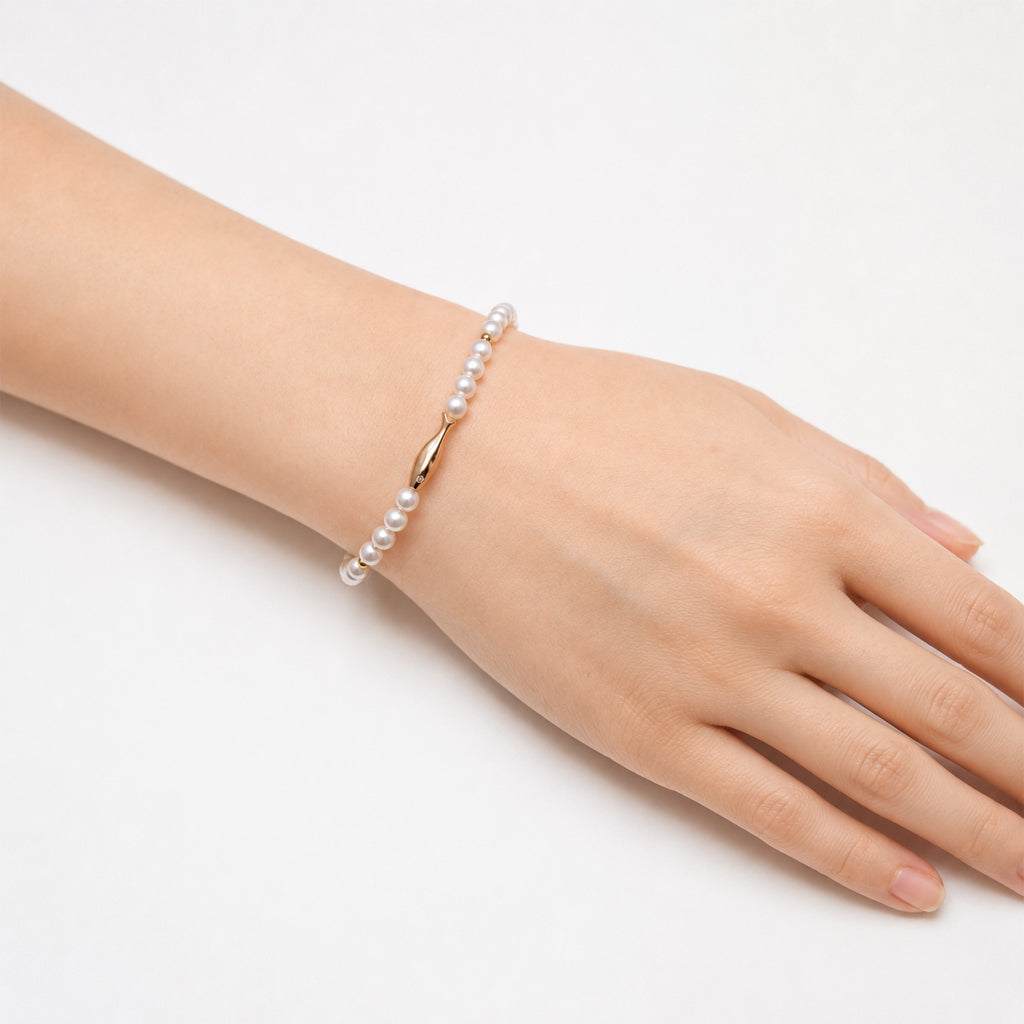 Freshwater pearl bracelet with alternating gold beads and gold fish charm on elastic band