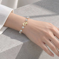 Freshwater Pearl Bracelet with iridescent white pearls, small gold-tone beads and a decorative gold toggle clasp.