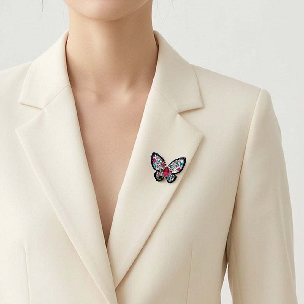 A close-up of a model wearing a cream-colored blazer with a colorful butterfly brooch pinned to the lapel.