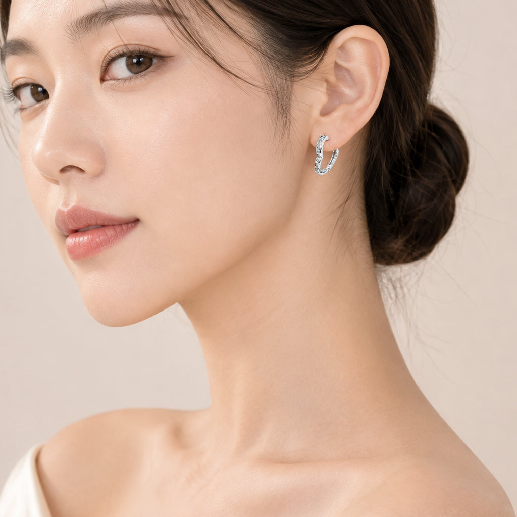 Heart-shaped cubic zirconia hoop earrings with rhodium plating and hinged clasp closure.