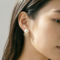 Close-up of gold plated freshwater pearl and cubic zirconia ribbon stud earrings with post backings