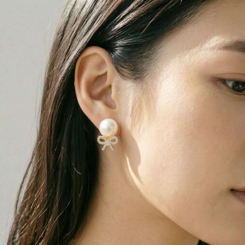 Close-up of gold plated freshwater pearl and cubic zirconia ribbon stud earrings with post backings
