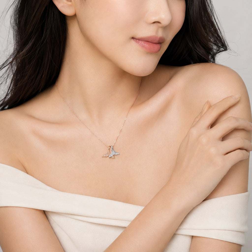 A close-up lifestyle shot of a model wearing a delicate mermaid tail necklace paired with a cream off-the-shoulder top.