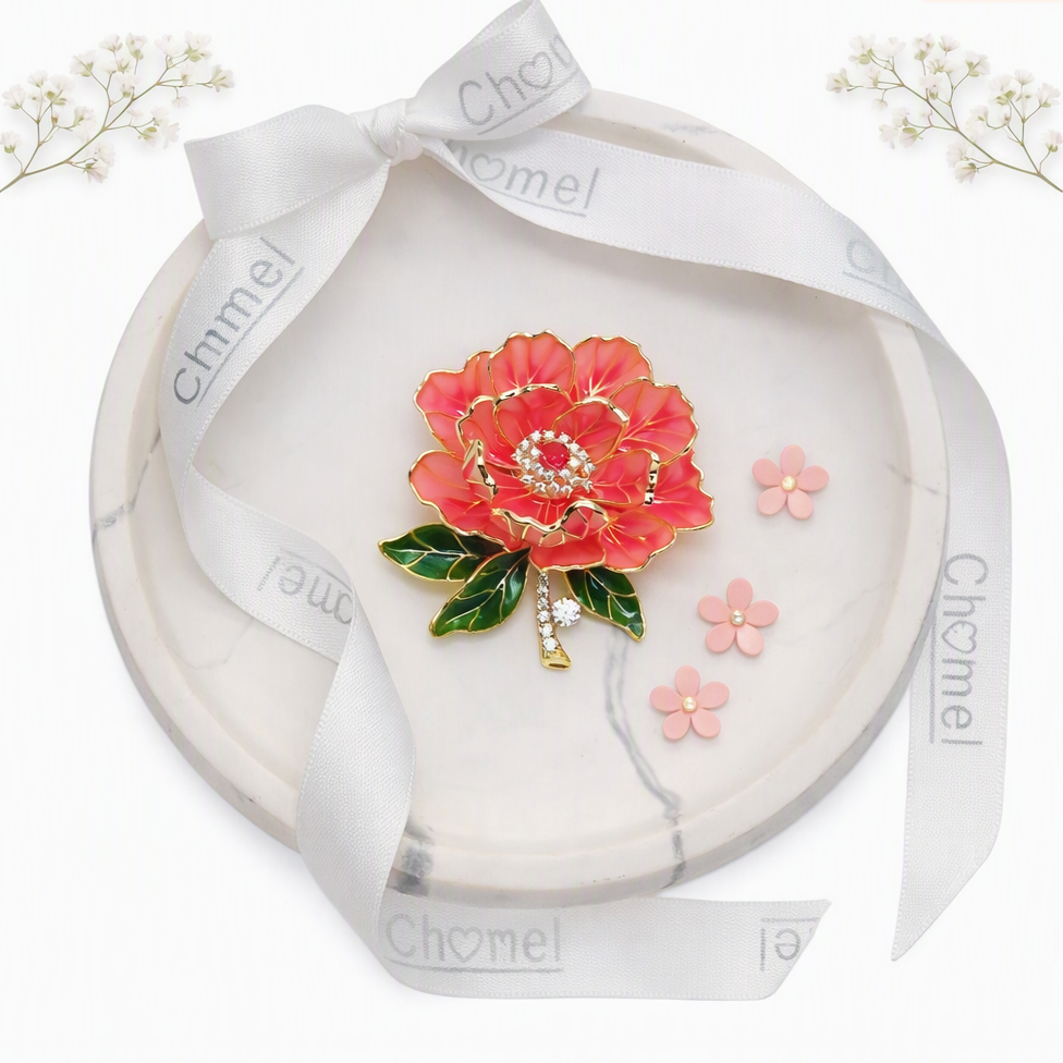Cubic Zirconia Brooch with coral-red enamel flower, green leaves, gold detailing and sparkling stones at the centre.
