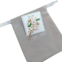 Cubic Zirconia Brooch with white flower-shaped stones, green accents and a gold-tone stem in a floral design.