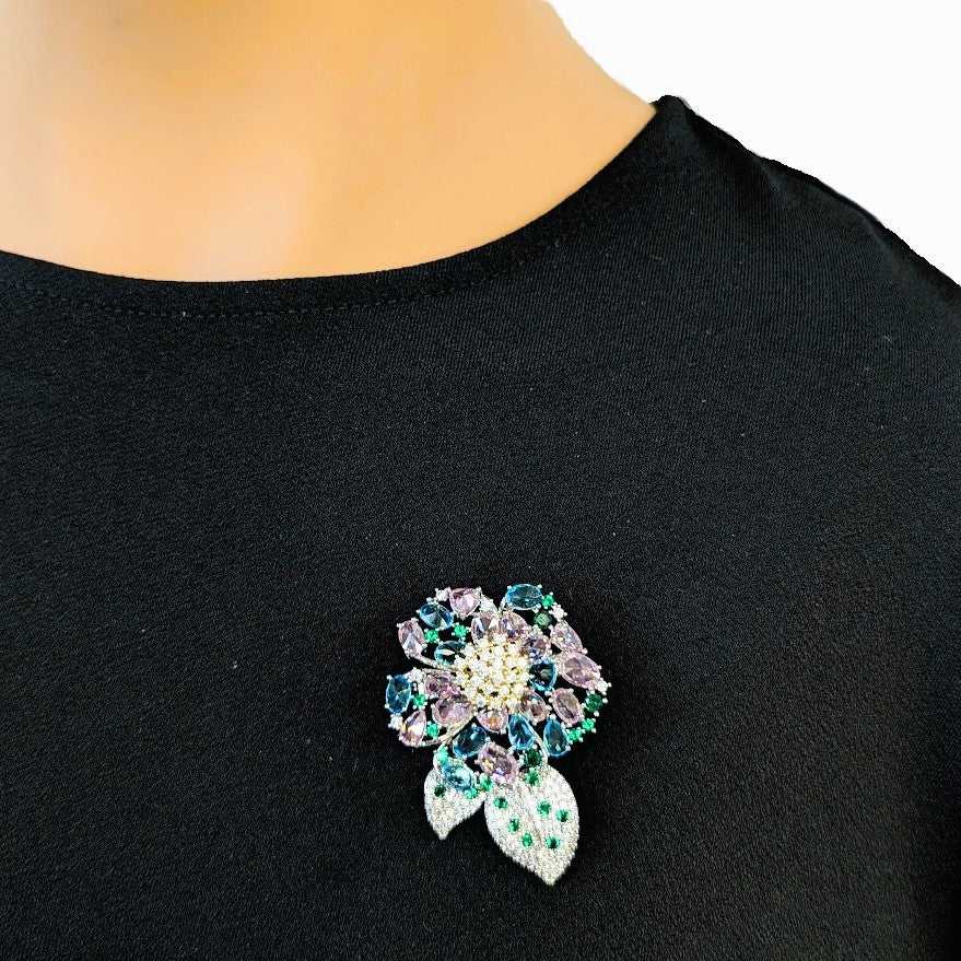Flower cubic zirconia brooch with pastel pink and blue stones, green leaf accents, rhodium plated, 3.6cm by 5cm size
