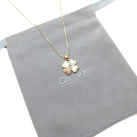 Clover pendant necklace in gold-tone metal with white mother-of-pearl petals and a sparkling accent; Butterfly Cubic Zirconia detail.