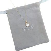 Gold-tone necklace with a delicate chain and white shell-shaped pendant, featuring a textured pearl-like surface; Butterfly Cubic Zirconia style.