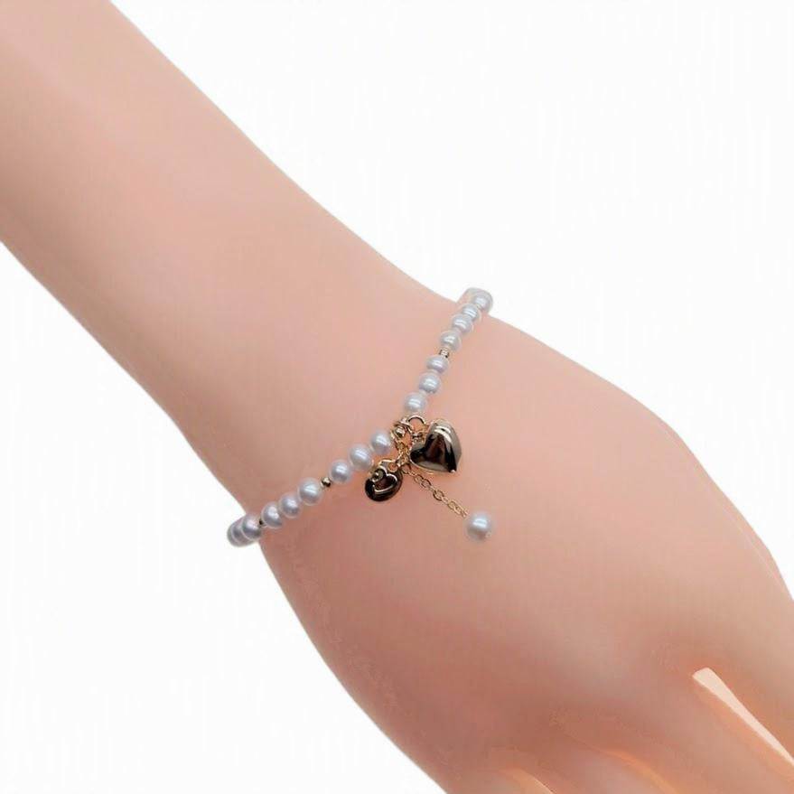 Freshwater pearl bracelet with alternating gold beads and gold heart charm on elastic band