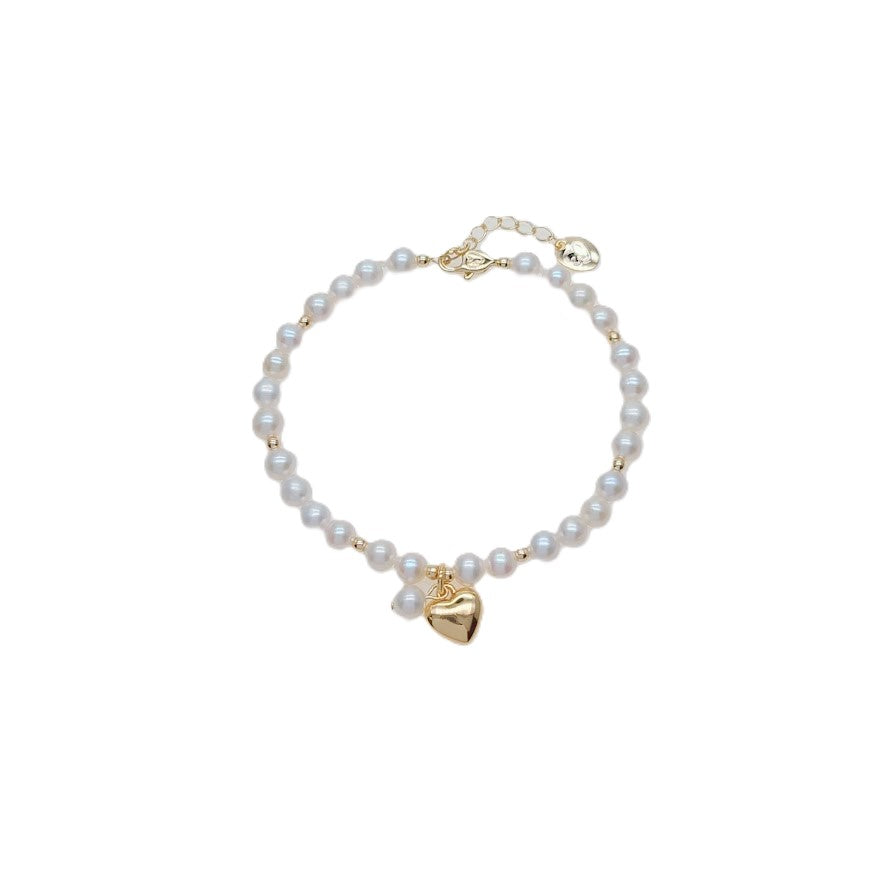 Freshwater Pearl Bracelet featuring lustrous white pearls with small gold beads and a gold plated heart charm centerpiece.