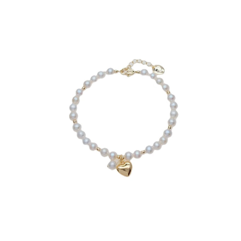 Freshwater Pearl Bracelet featuring lustrous white pearls with small gold beads and a gold plated heart charm centerpiece.