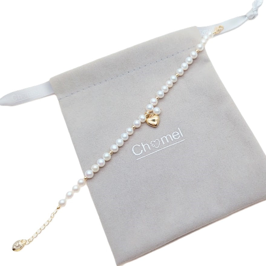 Freshwater Pearl Bracelet featuring white freshwater pearls and gold beads with a gold heart and pearl charm centerpiece