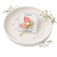 Flower Freshwater Pearl Brooch with pink enamel petals, gold-tone stem, sparkling clear stones and a central white pearl.