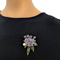 Flower Freshwater Pearl Brooch with clustered purple stones, a round white pearl, and slender green enamel leaves on a gold-tone setting.