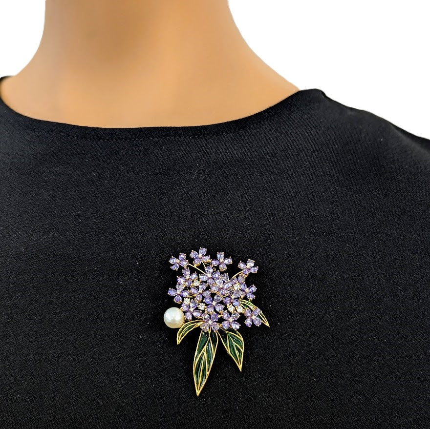 Flower Freshwater Pearl Brooch with clustered purple stones, a round white pearl, and slender green enamel leaves on a gold-tone setting.
