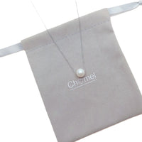 Freshwater Pearl Necklace with a single white pearl on a delicate rhodium plated chain resting on a grey pouch