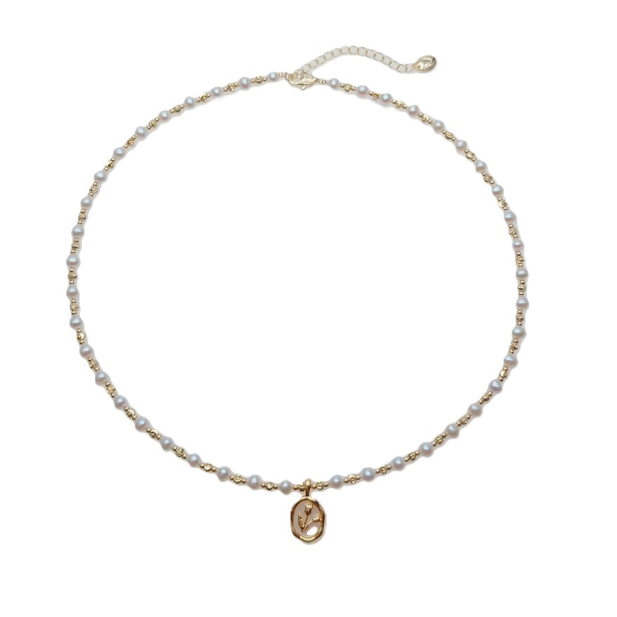 Freshwater Pearl Necklace with small round white pearls, gold-plated beads, and an oval gold pendant on a wire choker.