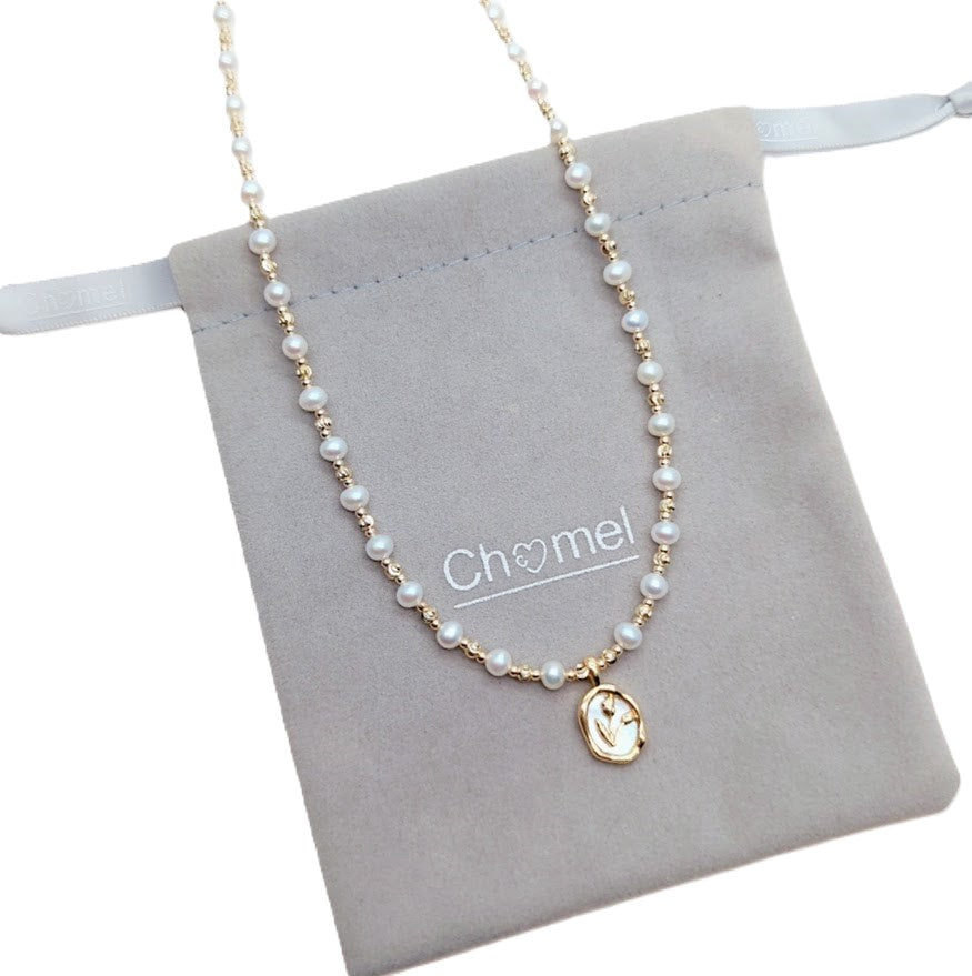 Freshwater Pearl Necklace featuring round white pearls and alternating gold-plated beads with a gold oval pendant on wire