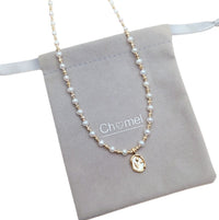 Freshwater Pearl Necklace featuring round white pearls and alternating gold-plated beads with a gold oval pendant on wire
