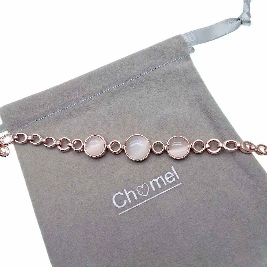 Rose gold-tone bracelet with three round pale pink stones set among oval links, shown with a soft fabric pouch.