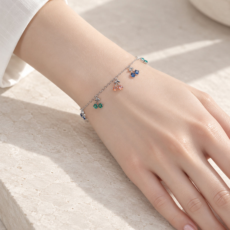 Cubic zirconia tennis bracelet with dangling colorful cherry charms and rhodium plated finish