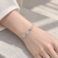 Cz bracelet with a delicate silver-tone chain, sparkling cubic zirconia clusters and a pale blue gourd-shaped charm.