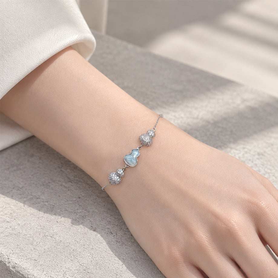 Cz bracelet with a delicate silver-tone chain, sparkling cubic zirconia clusters and a pale blue gourd-shaped charm.