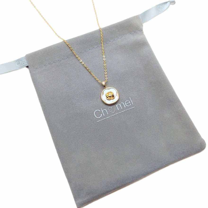 flower necklace with a fine gold-tone chain and round white pendant featuring a raised gold flower centerpiece