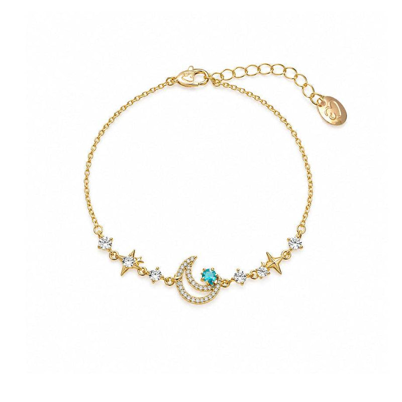 Gold-tone moon bracelet with a delicate chain, sparkling crescent moon, turquoise accent, clear stones, and star charms.
