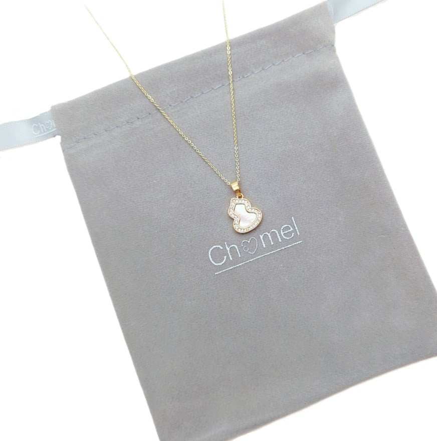 mother of pearl necklace with a gold-tone chain and small heart-shaped pendant edged in sparkling clear stones