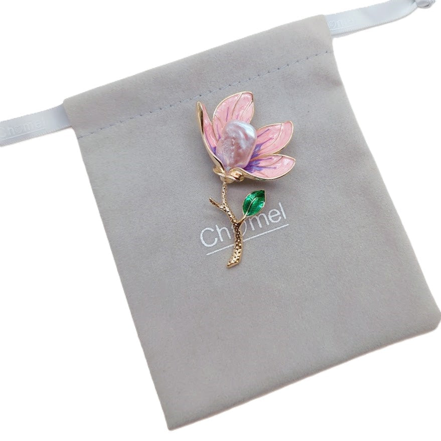 Flower pearl brooch with pink and lilac enamel petals, a green leaf, gold-tone stem and lustrous baroque pearl.