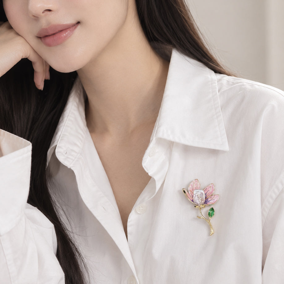 Flower pearl brooch with pink and purple enamel petals, a gold-tone stem and green leaf, and a white baroque pearl.