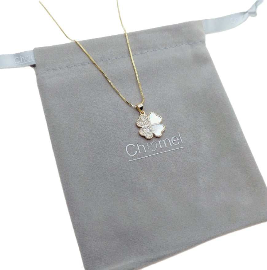 Pendant necklace with a gold-tone chain and four-leaf clover charm featuring white inlays and sparkling stones