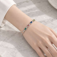 Adjustable slider bracelet with colorful rectangular cubic zirconia stones, bordered by small clear stones in a silver-tone setting.