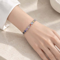 Slider bracelet with silver-tone metal and a row of colourful round stones, each framed by small clear stones.