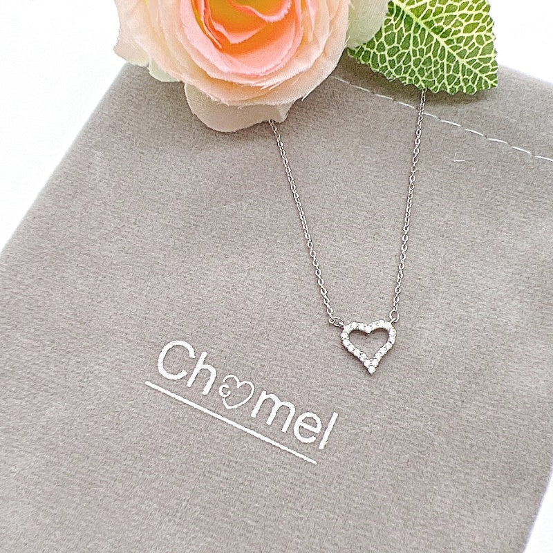 Heart cubic zirconia pendant necklace with rhodium plating on chain displayed with flower and pouch