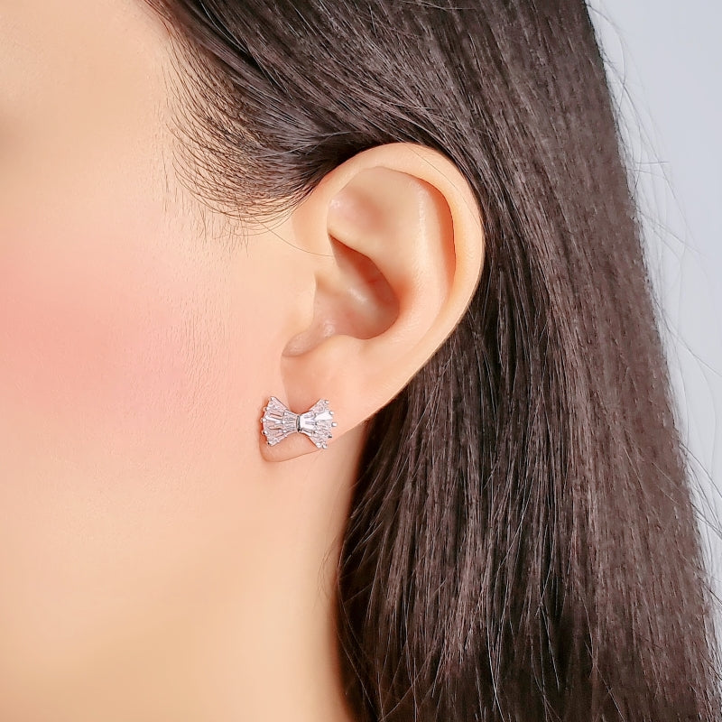 Ribbon cubic zirconia stud earrings with rhodium plating on ear