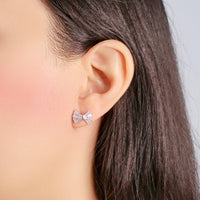 Ribbon cubic zirconia stud earrings with rhodium plating on ear