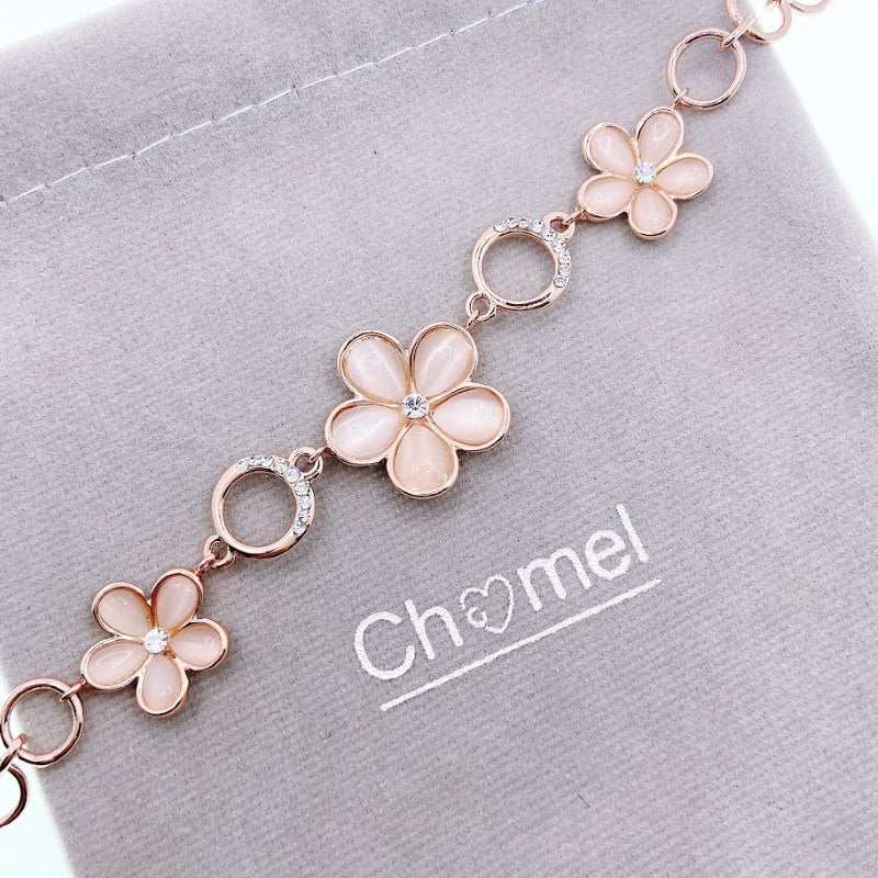Flower bracelet with rose gold-tone links, pale pink enamel petals, clear crystal accents and circular connectors.