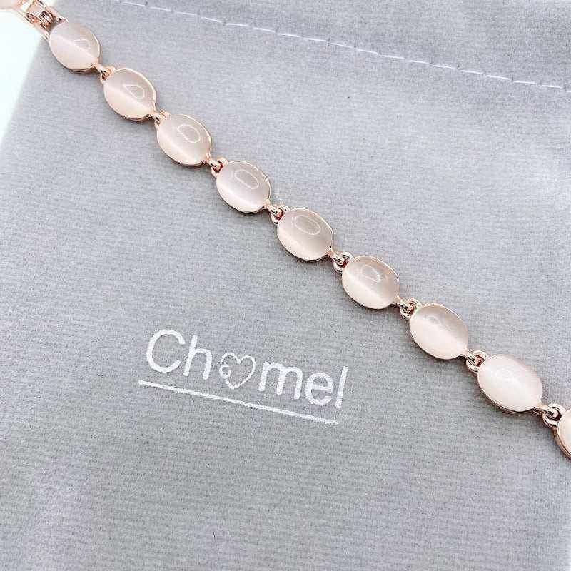 Rose gold tone bracelet with a linked row of smooth, pale pink oval stones and delicate metal connectors.