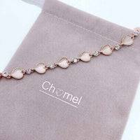 Rose gold-tone heart bracelet with pale pink heart-shaped stones alternating with clear round crystals along a delicate chain.